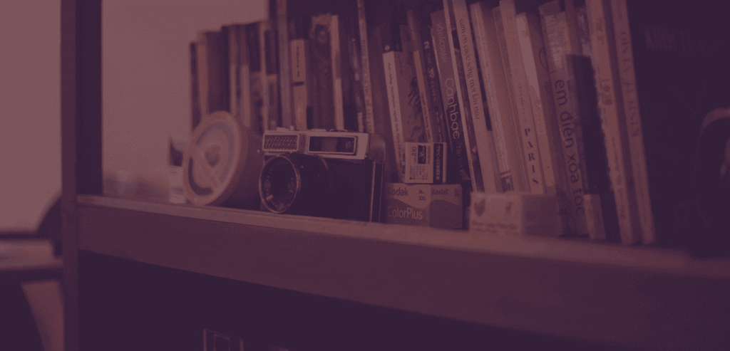 Ein Bücherregal gefüllt mit Büchern, Kodakfilmen. Eine alte Fotokamera steht vor den Büchern.